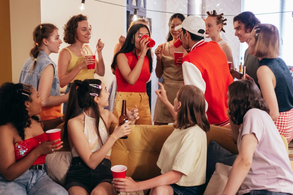 A vibrant group of young friends enjoying a house party with red cups and laughter indoors.