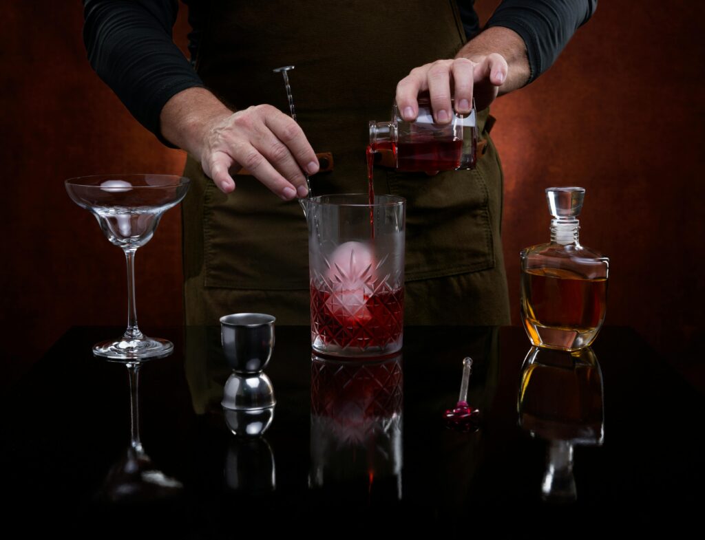 A professional bartender skillfully prepares a classic cocktail with precision, showcasing a sophisticated bar scene.